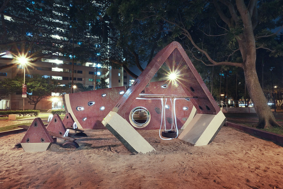 Mosaic-tiled watermelon playground lit at night